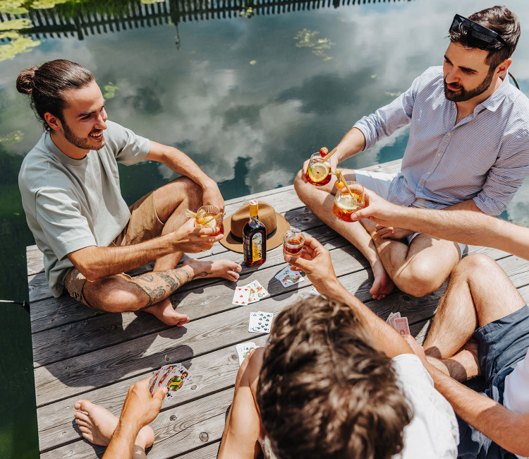 Vier Freunde spielen Karten und trinken Gurktaler Alpenkräuter